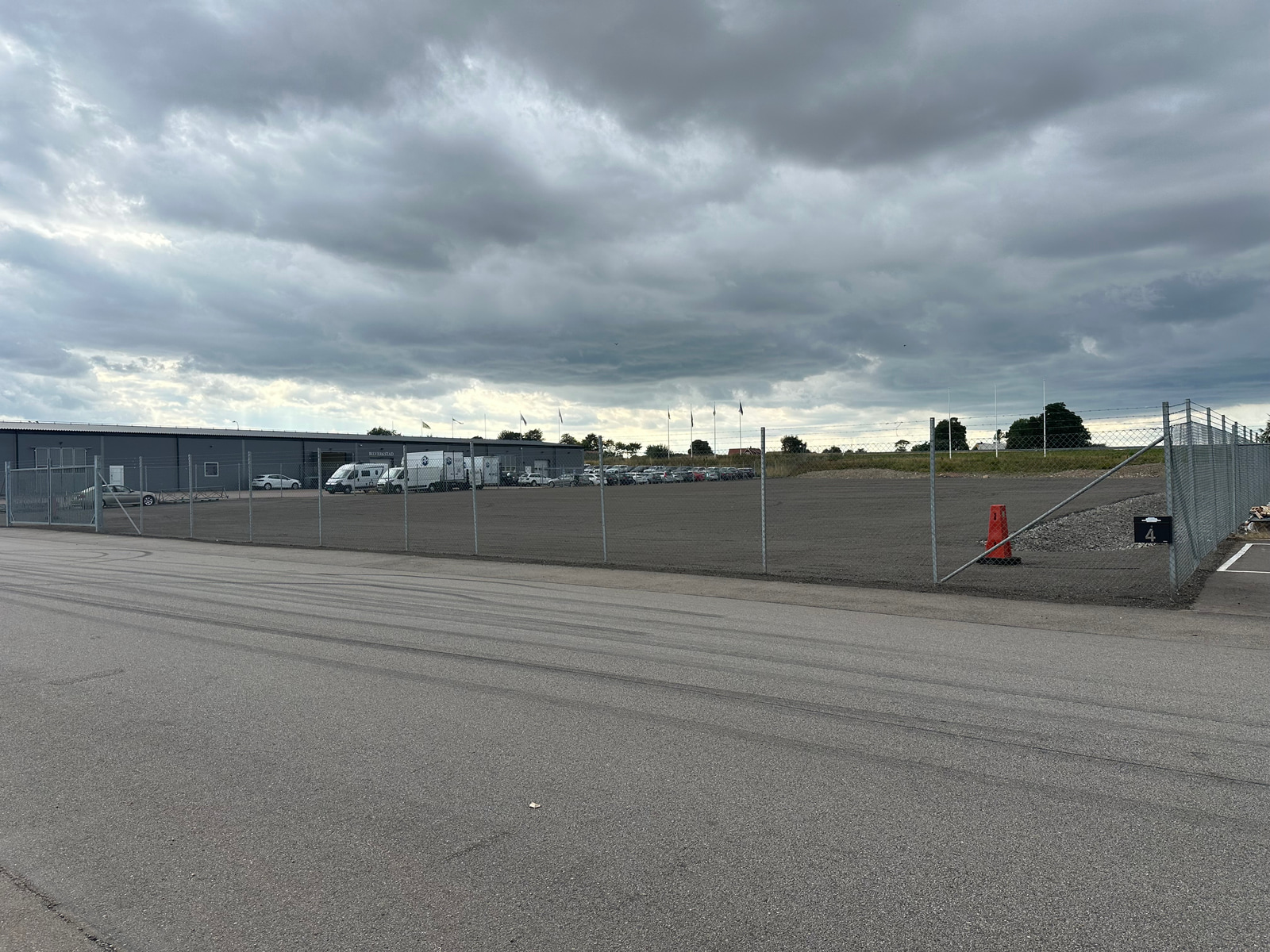 Industritomten sedd från Spannmålsgatan: en stor, öppen och hårdgjord yta bakom ett stängsel, med industribyggnader i bakgrunden.